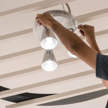 Engenheiros elétricos a instalar lâmpadas de teto no corredor